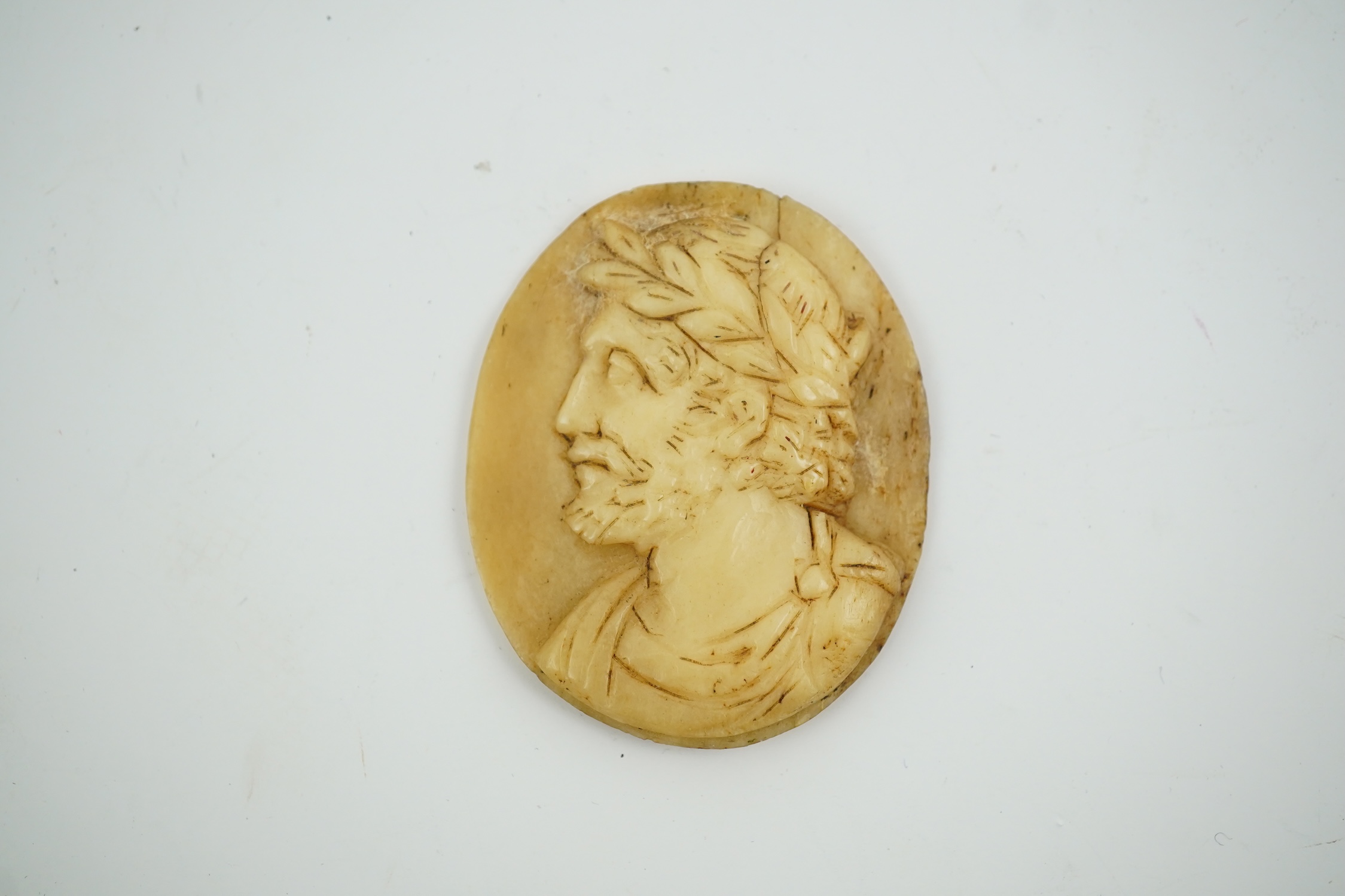 An 18th century unmounted oval horn cameo, carved with the head of Caesar to dexter, 49mm. Condition - poor